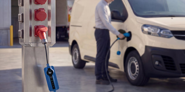 Driver charging a white electric van from a red CEE power pillar with a Voldt® cable